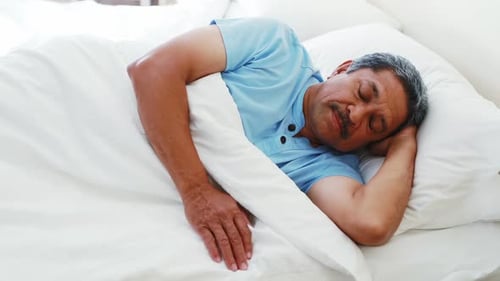 Senior man sleeping peacefully on bed 4k