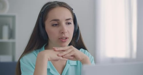 Glückliche junge Geschäftsfrau trägt Headset spricht mit Webkamera Distanz Online-Videokonferenz