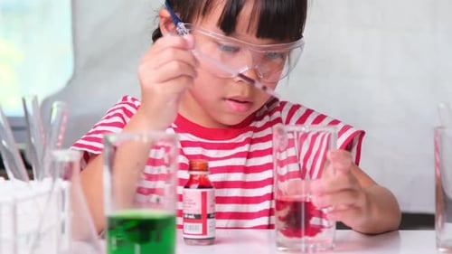 Girl Mixes Liquid in Beaker with Dropper