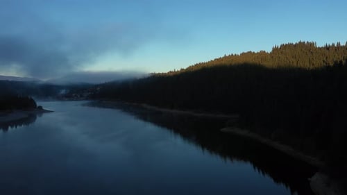 Flying Over a Lake in Misty Dawn Lights in Early Morning. Aerial View