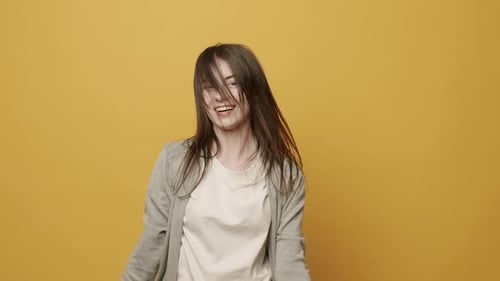 Excited Woman Dancing with Hair Against Yellow Background