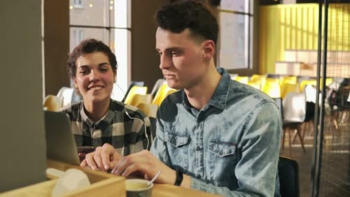Young Adults Collaborate On Laptop in Bright Workplace