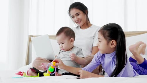 Mother and Children Playing Together on Bed