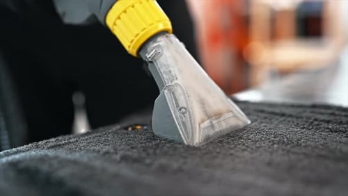 Working cleaner at car wash. Cleaning a carpet using a professional vacuum cleaner. Slow motion