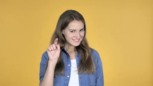 Smiling Woman Points Finger on Yellow Background