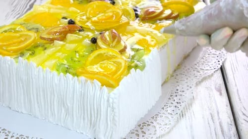 Close Up of Baker Decorating Fruit Topped Cake