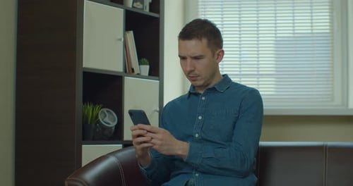 Man On Couch Looking At His Phone