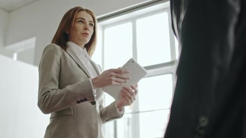 Businesswoman Shakes Hands with Businessman in Office Setting