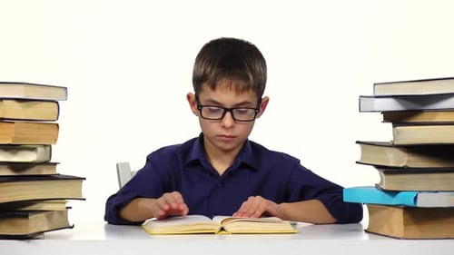 Junge sitzt am Tisch und blättert durch die Seiten eines Buches. Weißer Hintergrund.