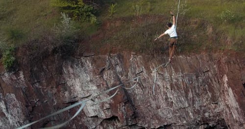 Man Balances on Tightrope Above Rocky Cliff