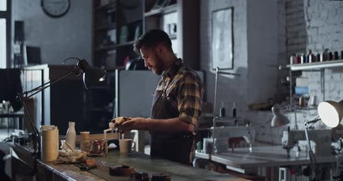 Man Working at Table in Cluttered Workshop