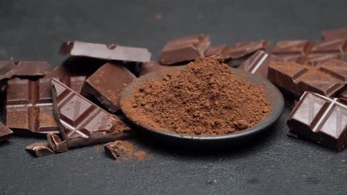 Dark or Milk Organic Chocolate Pieces and Cocoa Powder on Dark Concrete Background