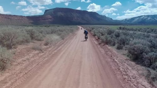 Aerial drone view of a motocross motorcycle driving off-road on a dirt road in Moab, Utah