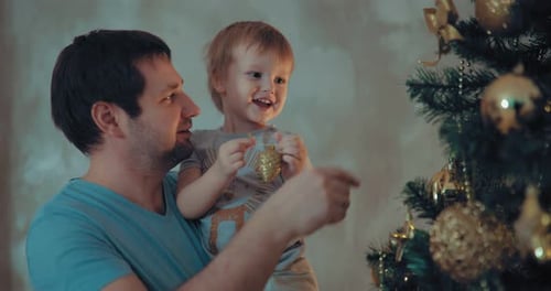 Dad and Child Decorating Christmas Tree with Ornaments