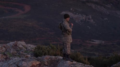 Soldier Standing Guard on Mountain at Sunrise