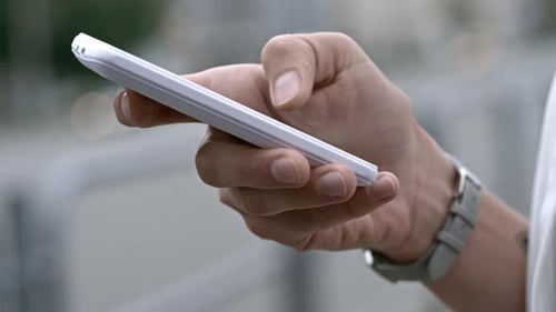 Hand Holding Mobile Phone in Urban Setting