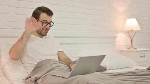 Man On Laptop Waving in Bed