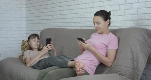 Mother and Daughter Using Smart Phones on Couch