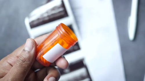 Hand Holding Prescription Bottle with Pills