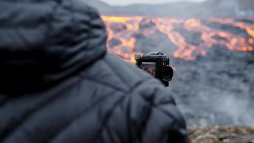 Photographer Filming Dramatic Flowing Lava Landscape