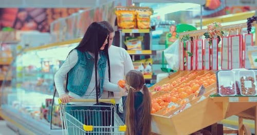 Father Mother and Little Daughter Choosing Fruits in Supermarket