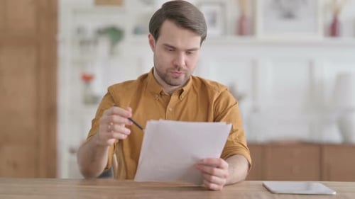Young Man Celebrating Success on Document in Office