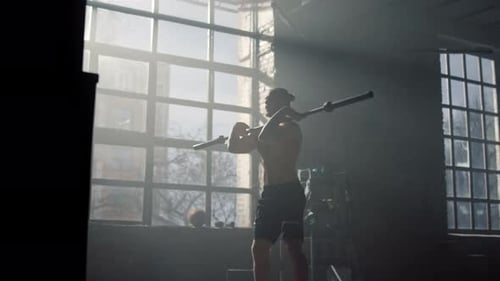 Man Performing Squats with Barbell in Gym