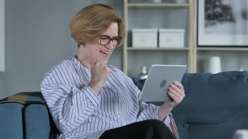 Woman Sitting on Couch Reacting to Tablet Device