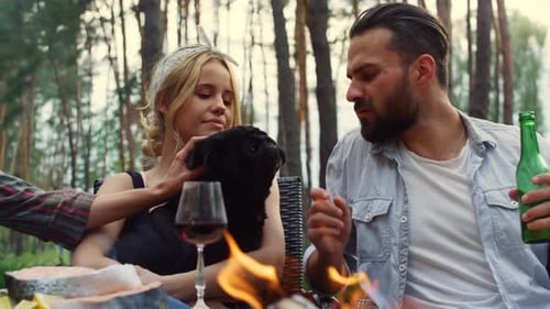 Friends Gather Around Campfire with Dog in Forest