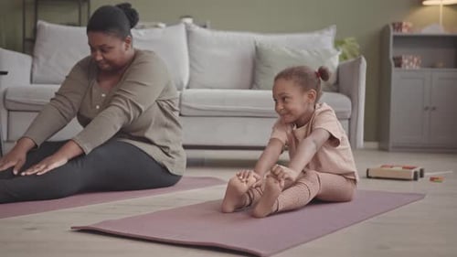 Woman and Child Stretching on Yoga Mats at Home