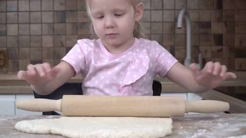 Girl Rolls Dough with Rolling Pin in Kitchen