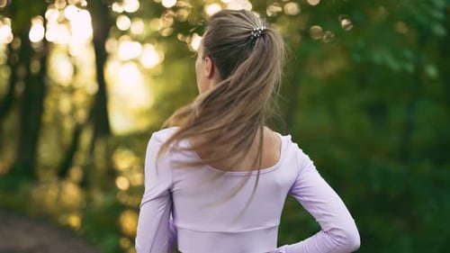 A Young Woman Runner is Training in Summer Park