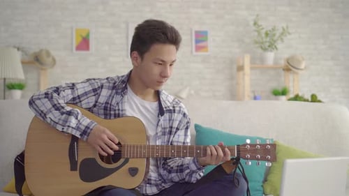 Young Adult Plays Guitar at Home