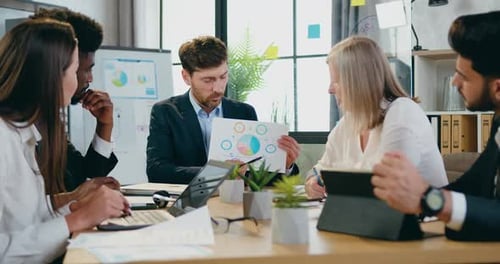 Businesspeople Working Together in Office Room and Discussing Reports with Chart
