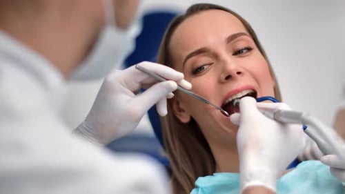 Close Up Face of Female Patient with Open Mouth During Treating Teeth