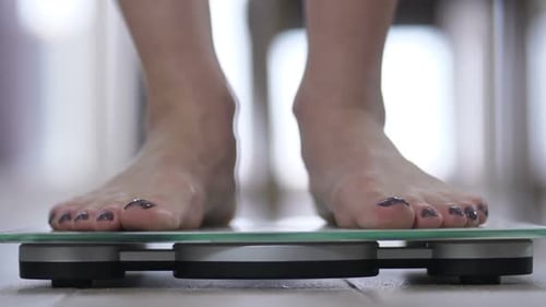 Woman Weighing Herself on Modern Glass Scale