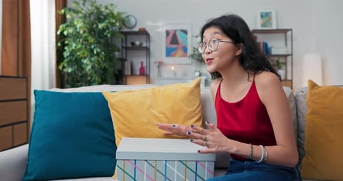 Woman Opens Gift and Tells Story on Couch