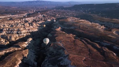 Aerial View on Flying Colored Balloons Over Valley with Volcanic Hills Forming Gorges and Canyon