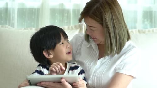 Child and Woman Using Tablet Together Indoors