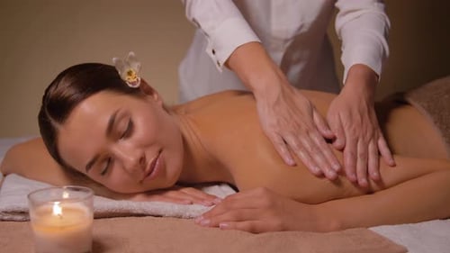 Liegende Frau und Rückenmassage im Spa