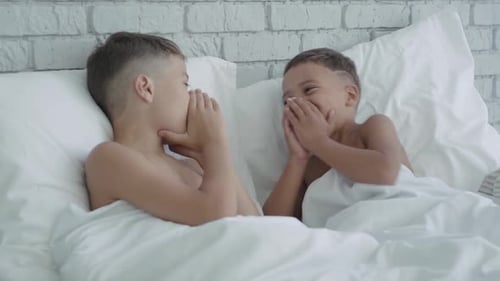 Two Young Boys Whisper Secrets in Bed