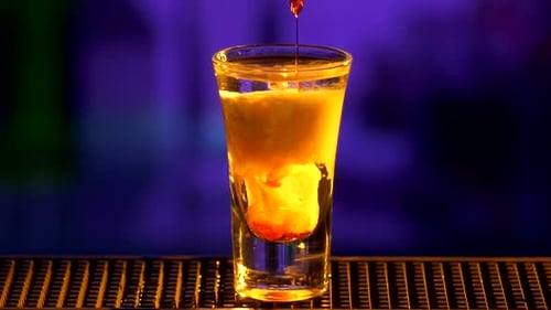 Barkeeper macht weiter, gießt Cocktail mit weißer Alkoholflüssigkeit ein, fügt Rot hinzu, Shots, langsam
