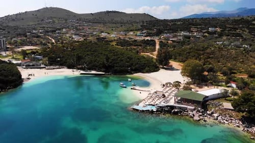 Luftaufnahme eines weißen Sandstrandes mit vielen Liegestühlen ohne Menschen an einem sonnigen Tag am