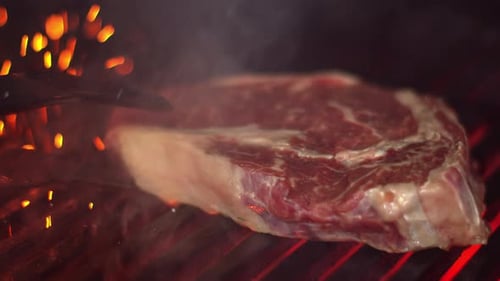 The Cook Turns a Piece of Meat on the Grill with Meat Tongs. Delicious Piece of Meat with Grilled