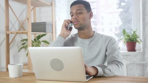 Young Adult Answers Cell Phone While Using Laptop