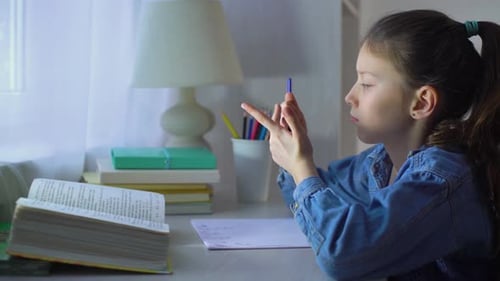 Little School Girl Counting on Fingers while Doing her Homework