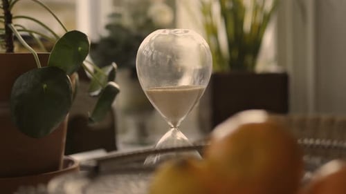 Elegant Hourglass Sand Flowing on a Reflective Table