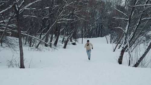Fit man running on snow in winter forest