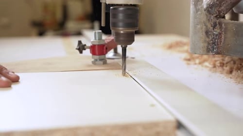 Drill bit bores into wood on workshop machine