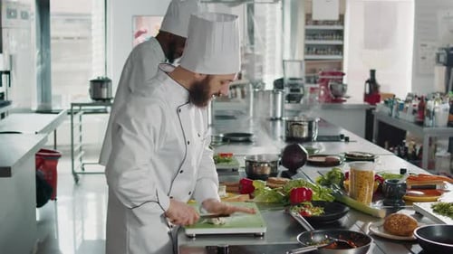 Joven chef cortando diente de ajo natural en tabla de cortar